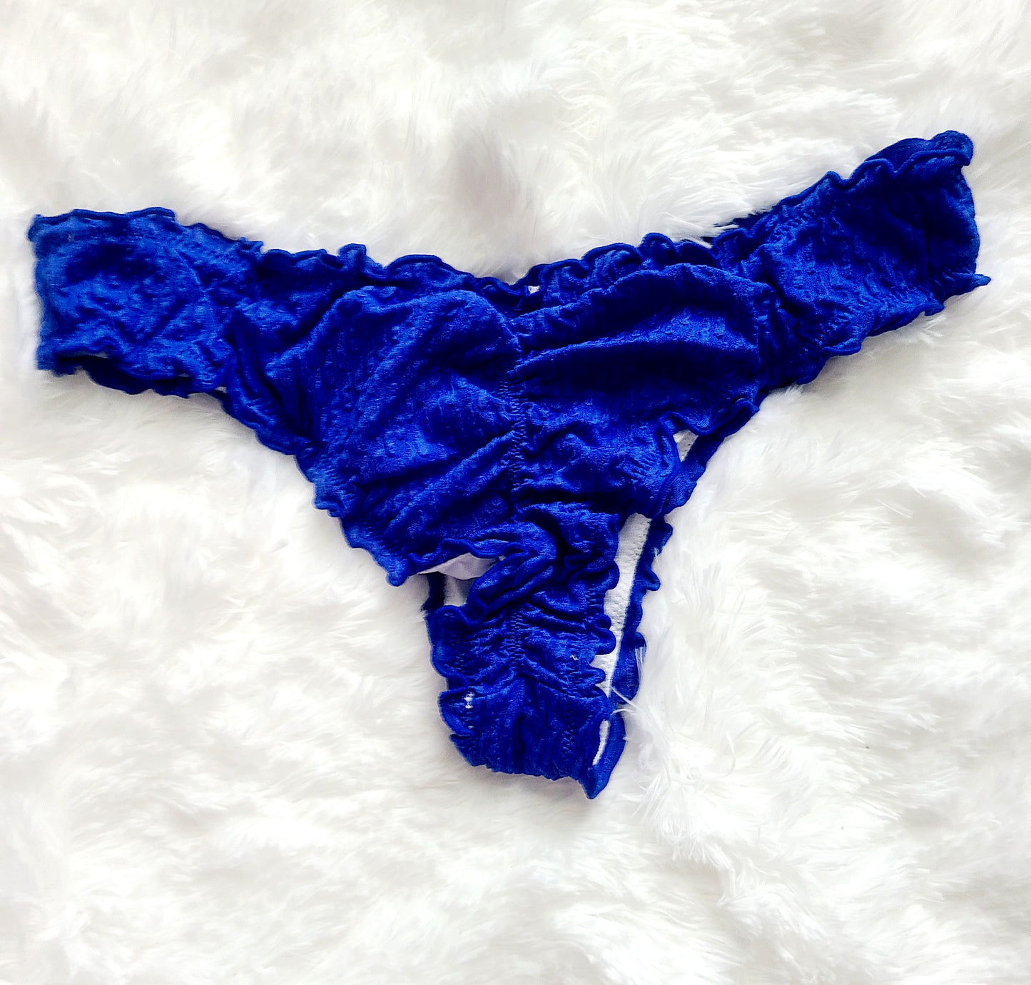 A woman wearing a ruffled bikini top with tie straps and removable pads, paired with matching cheeky bottoms with a central seam on the back.