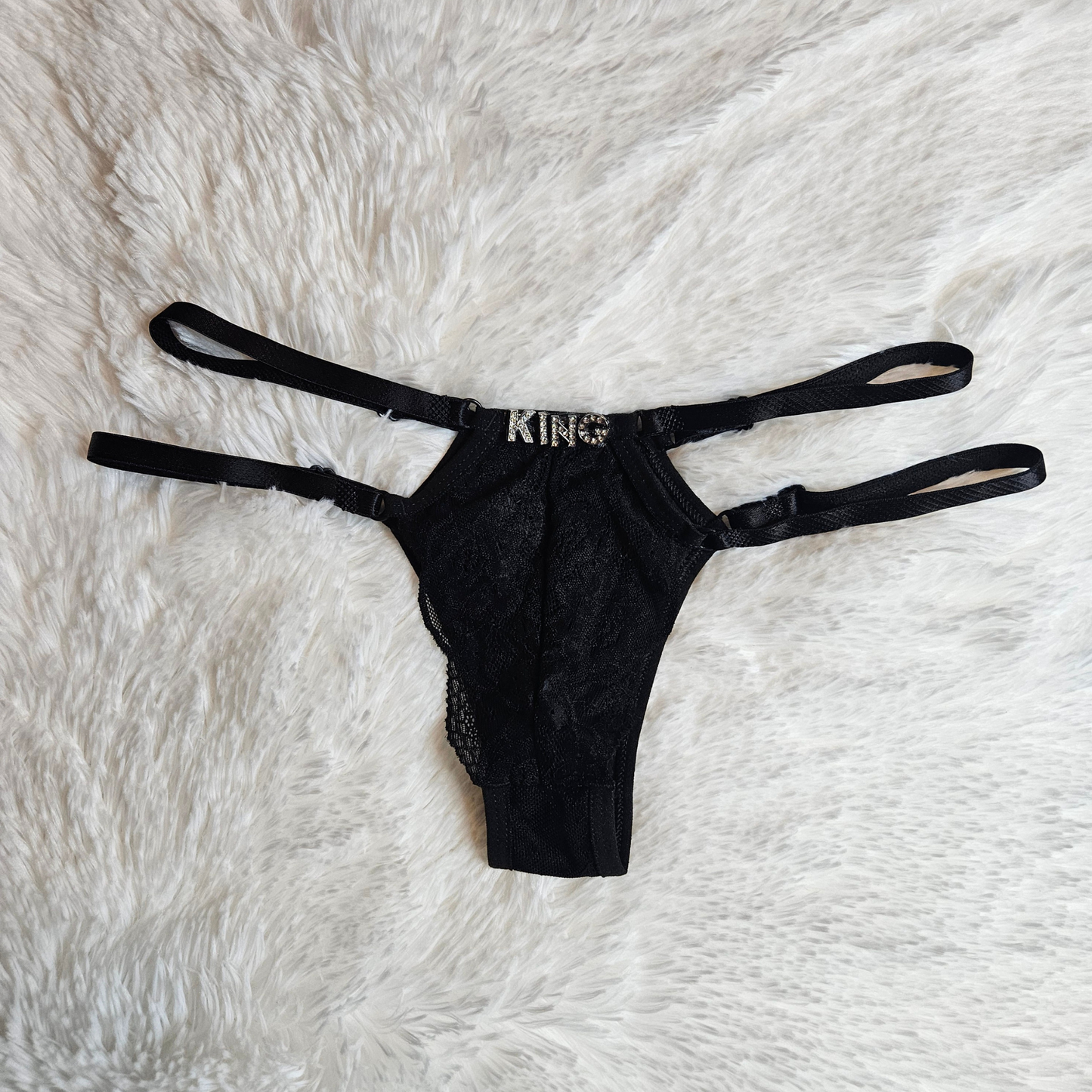 Boutique black floral lace G-string with a KING rhinestone statement and signature gold-toned adjustable sliders.