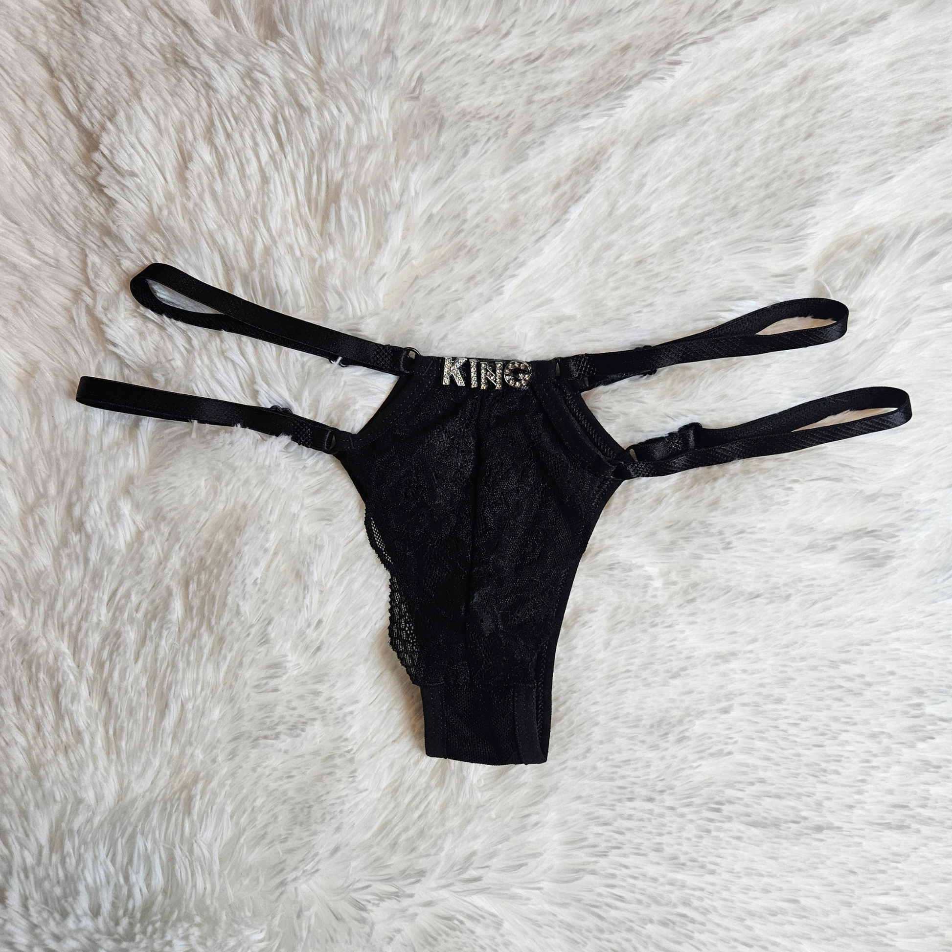 Boutique black floral lace G-string with a KING rhinestone statement and signature gold-toned adjustable sliders.