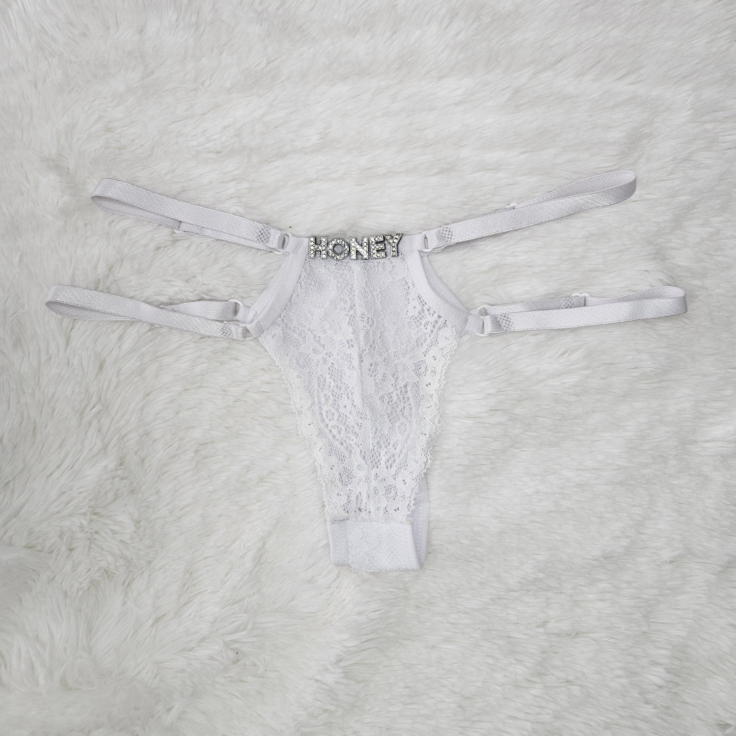 Brilho Adjustable Strappy Lace G-String in White featuring a hand-set HONEY rhinestone statement and four satin adjustable straps.